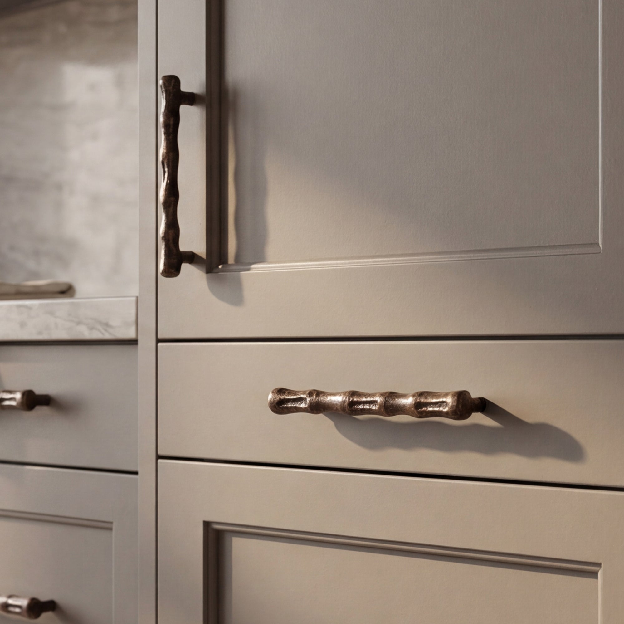 Handcast bronze appliance pulls shown on paneled kitchen cabinetry for refined appliance and tall cabinet applications.